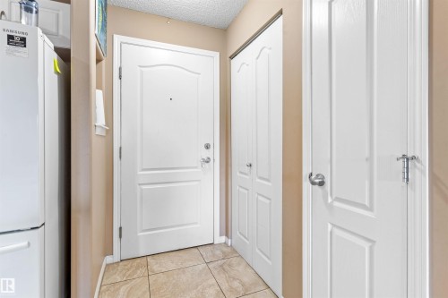This entry area features light-colored tile flooring, white interior doors, and neutral wall paint - 224 3425 19 Street Nw, Edmonton, AB - Indoor Photo Showing Other Room
