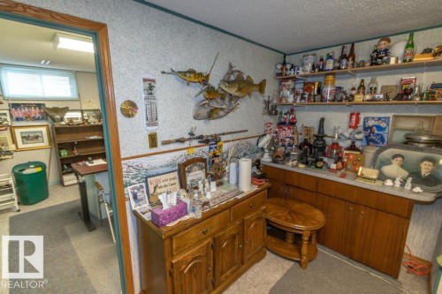 The property features a room with wood cabinetry, shelving, and a counter space, with access to an additional room - 5013 45 St, St. Paul Town, AB - Indoor Photo Showing Other Room