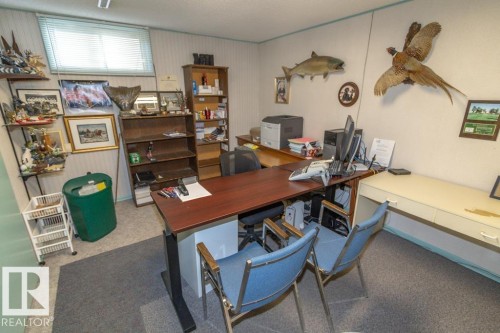 This room features a window with horizontal blinds, carpeted flooring, and a built-in desk area - 5013 45 St, St. Paul Town, AB - Indoor Photo Showing Office