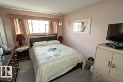 The bedroom features a window with curtains, a bed with a headboard, and soft carpeted flooring - 