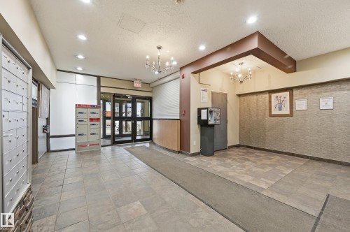 The property features a welcoming common area with tiled flooring, recessed lighting, and decorative chandeliers - 209 9710 105 Street Nw, Edmonton, AB - Indoor Photo Showing Other Room