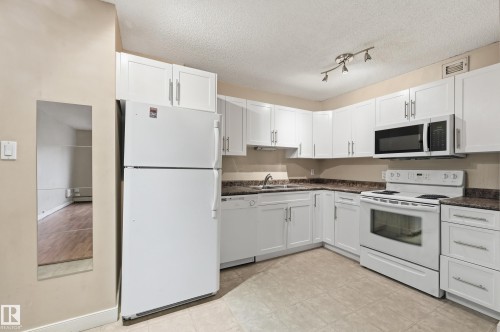 Kitchen featuring white cabinetry, a microwave, an electric range, and a refrigerator - 209 9710 105 Street Nw, Edmonton, AB - Indoor Photo Showing Kitchen With Double Sink