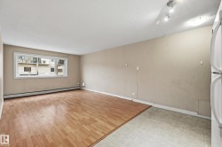 The open-concept living area features a mix of wood-style flooring and tiled flooring, with a window providing outdoor views - 