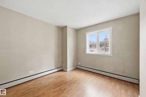 This room features light-colored walls and wood flooring, complemented by a window providing natural light - 209 9710 105 Street Nw, Edmonton, AB - Indoor Photo Showing Other Room