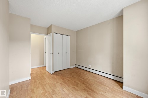 This room features neutral-toned walls, light wood flooring, and a closet with bifold doors - 209 9710 105 Street Nw, Edmonton, AB - Indoor Photo Showing Other Room