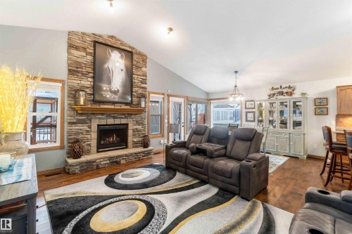 The living area features hardwood floors and a stone fireplace with a natural wood mantel - 61 Linkside Blvd, Spruce Grove, AB - Indoor Photo Showing Living Room With Fireplace