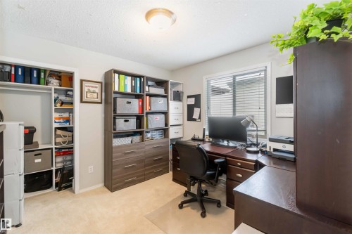 This versatile room features neutral-toned carpeting, a window with horizontal blinds, and a built-in closet with shelving - 61 Linkside Blvd, Spruce Grove, AB - Indoor Photo Showing Office