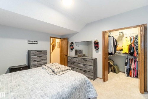 The property features a bedroom with light blue walls, a neutral-toned carpet, and a closet with bifold doors - 61 Linkside Blvd, Spruce Grove, AB - Indoor Photo Showing Bedroom