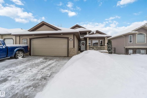The property features a front-facing garage, a covered entry porch, and a stone facade detail - 61 Linkside Blvd, Spruce Grove, AB - Outdoor With Facade