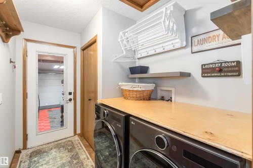 The laundry area features a wooden countertop, light gray walls, and practical shelving - 61 Linkside Blvd, Spruce Grove, AB - Indoor Photo Showing Laundry Room