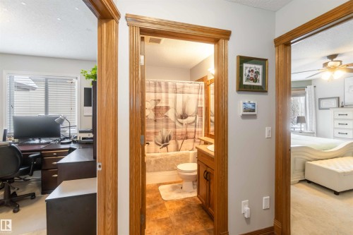 This property features an office space with a large window, a bathroom with a shower and tub, and a bedroom with a ceiling fan - 61 Linkside Blvd, Spruce Grove, AB - Indoor Photo Showing Office
