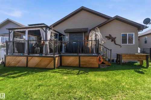 Expansive backyard featuring a manicured lawn and a multi-level deck with a dark railing system - 61 Linkside Blvd, Spruce Grove, AB - Outdoor With Deck Patio Veranda