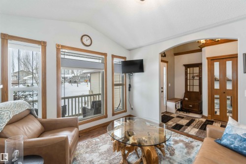 The living area features vaulted ceilings, large windows with wood trim, and hardwood flooring - 61 Linkside Blvd, Spruce Grove, AB - Indoor Photo Showing Living Room