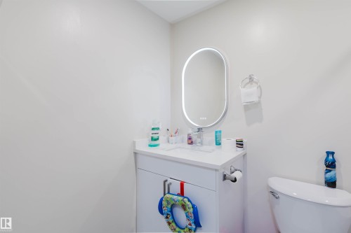 Bathroom featuring a white vanity with a white countertop, a white sink, and an illuminated oval mirror - 18088 93 Avenue Nw, Edmonton, AB - Indoor Photo Showing Bathroom
