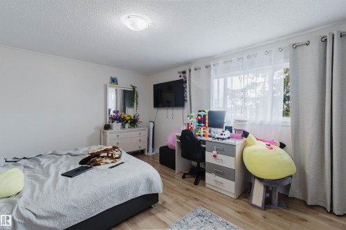 Bedroom featuring light-colored walls, a window with sheer and opaque curtains, and light wood flooring - 18088 93 Avenue Nw, Edmonton, AB - Indoor Photo Showing Bedroom