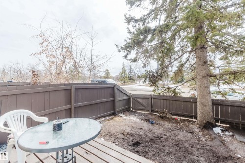The property features a fenced yard with a large evergreen tree and a small wooden gate - 18088 93 Avenue Nw, Edmonton, AB - Outdoor With Deck Patio Veranda