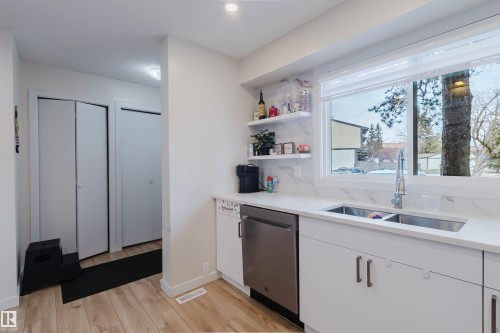 Kitchen featuring white cabinetry, a double basin sink, stainless steel dishwasher, and a large window - 18088 93 Avenue Nw, Edmonton, AB - Indoor Photo Showing Kitchen With Double Sink