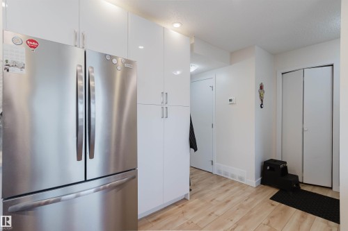 The property features a kitchen with a stainless steel refrigerator and white cabinetry, complemented by light-toned flooring - 18088 93 Avenue Nw, Edmonton, AB - Indoor