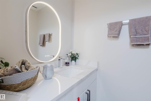 Bathroom vanity featuring a rectangular undermount sink, a chrome faucet, and a large illuminated oval mirror - 18088 93 Avenue Nw, Edmonton, AB - Indoor Photo Showing Bathroom