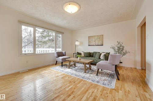 Living area featuring hardwood flooring, light-colored walls, and a large window providing natural light - 10940 71 Avenue, Edmonton, AB - Indoor Photo Showing Living Room