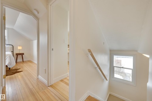 The property features hardwood floors in the hallway and a room with an angled ceiling - 10940 71 Avenue, Edmonton, AB - Indoor Photo Showing Other Room