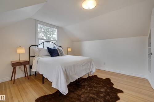 This inviting room features hardwood floors, a sloped ceiling, and a window providing natural light - 10940 71 Avenue, Edmonton, AB - Indoor Photo Showing Bedroom