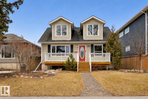 Charming property featuring a light-colored exterior with dormer windows, a red front door, and a front deck with white railings - 10940 71 Avenue, Edmonton, AB - Outdoor With Deck Patio Veranda