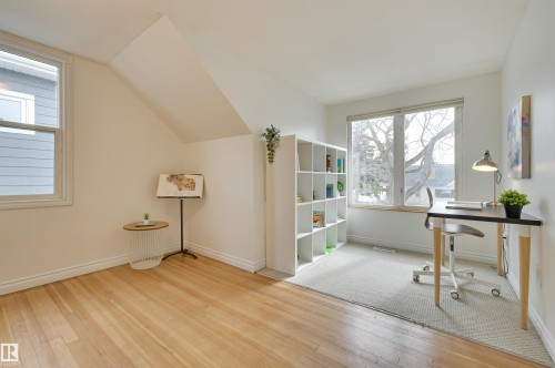 This bright room features a large window, hardwood flooring, and a portion of the ceiling with a sloped design - 10940 71 Avenue, Edmonton, AB - Indoor