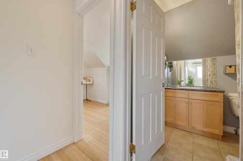 Bathroom vanity with light wood cabinetry, a dark countertop, and an integrated sink, complemented by tiled flooring - 10940 71 Avenue, Edmonton, AB - Indoor Photo Showing Other Room