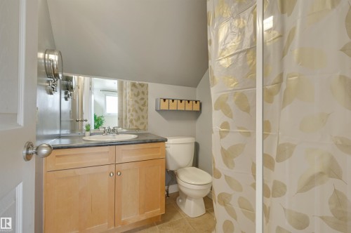The bathroom features a vanity with light wood cabinetry, a white basin sink, and a dark countertop - 10940 71 Avenue, Edmonton, AB - Indoor Photo Showing Bathroom