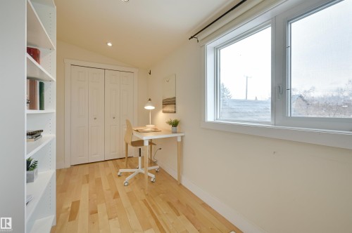 The room features hardwood floors, a large window, recessed lighting, and a built-in shelving unit - 10940 71 Avenue, Edmonton, AB - Indoor Photo Showing Other Room