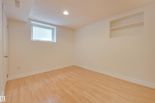 This room features light-toned hardwood flooring, a window providing natural illumination, and an integrated wall niche with shelving - 10940 71 Avenue, Edmonton, AB - Indoor Photo Showing Other Room