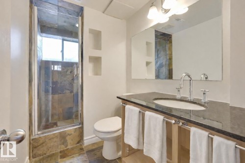 The bathroom features a walk-in shower with natural stone tiling and a glass enclosure - 10940 71 Avenue, Edmonton, AB - Indoor Photo Showing Bathroom