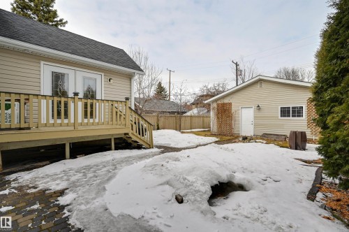 The property features an exterior with light-colored siding, a dark roof, and a wooden deck with railing and stairs - 10940 71 Avenue, Edmonton, AB - Outdoor
