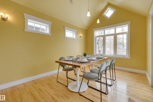 This bright room features hardwood floors, a vaulted ceiling, and multiple windows allowing for natural light - 10940 71 Avenue, Edmonton, AB - Indoor Photo Showing Dining Room