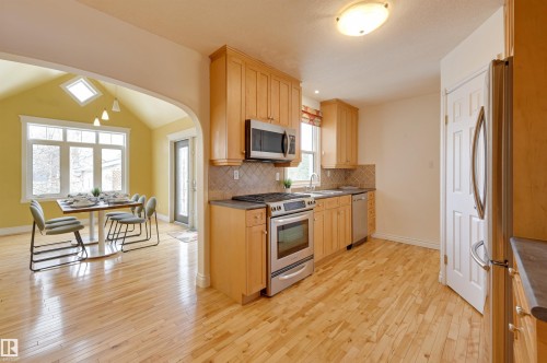 The kitchen features wood cabinetry, stainless steel appliances, and light-colored hardwood flooring - 10940 71 Avenue, Edmonton, AB - Indoor Photo Showing Kitchen