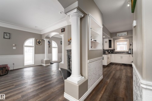 This inviting living space features dark wood-style flooring, arched windows, and decorative columns - 4403 Yeoman Drive, Onoway, AB - Indoor Photo Showing Other Room