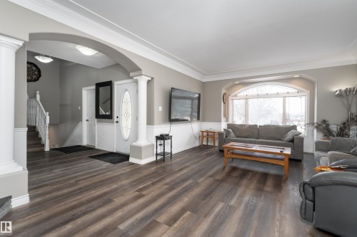 The property features hardwood floors, an arched entryway, and a prominent front door with decorative glass - 4403 Yeoman Drive, Onoway, AB - Indoor Photo Showing Living Room