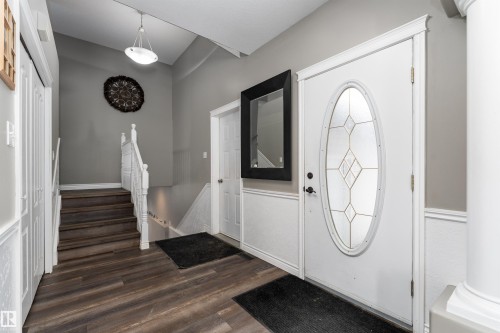 Inviting entryway featuring dark wood-style flooring, a decorative front door with an oval-shaped stained glass insert, and wainscoting along the walls - 4403 Yeoman Drive, Onoway, AB - Indoor Photo Showing Other Room