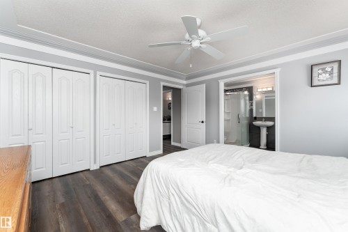 The property features a room with dark wood-style flooring, white bi-fold closet doors, and crown molding - 4403 Yeoman Drive, Onoway, AB - Indoor Photo Showing Bedroom