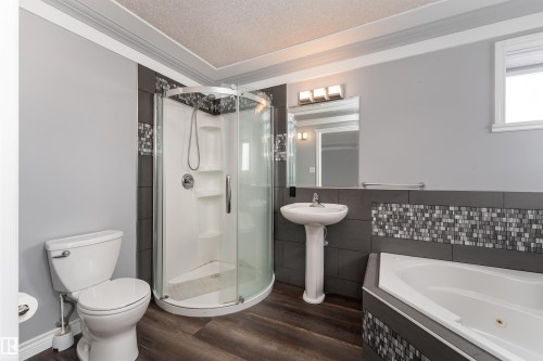 Bathroom featuring a corner shower, a separate bathtub, a pedestal sink, and wood-style flooring - 4403 Yeoman Drive, Onoway, AB - Indoor Photo Showing Bathroom