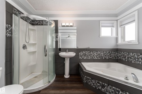 The bathroom features a corner shower with a glass enclosure, a pedestal sink, and a built-in tub with decorative tile surround - 4403 Yeoman Drive, Onoway, AB - Indoor Photo Showing Bathroom