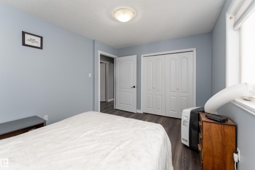 The room features light blue walls, dark wood-style flooring, a white ceiling, and a white bi-fold closet door - 4403 Yeoman Drive, Onoway, AB - Indoor Photo Showing Bedroom