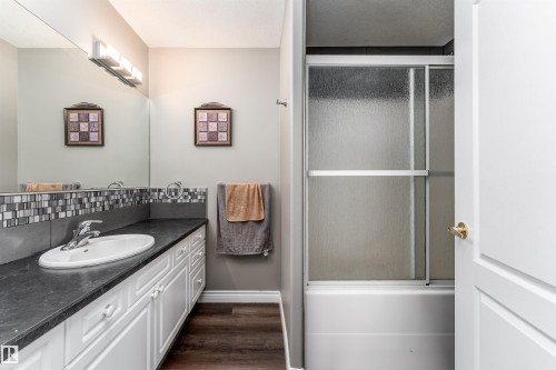 The bathroom features a vanity with a white sink, dark countertop, and white cabinetry - 4403 Yeoman Drive, Onoway, AB - Indoor Photo Showing Bathroom