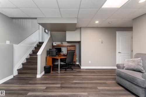 This area features durable wood-look flooring, a staircase with white risers and dark treads, and a drop ceiling with recessed lighting - 4403 Yeoman Drive, Onoway, AB - Indoor Photo Showing Other Room