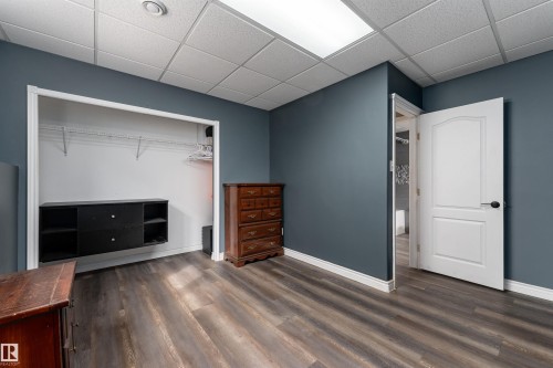 This room features wood-style flooring, a drop ceiling with recessed lighting, and a closet with a built-in storage unit and shelving - 4403 Yeoman Drive, Onoway, AB - Indoor