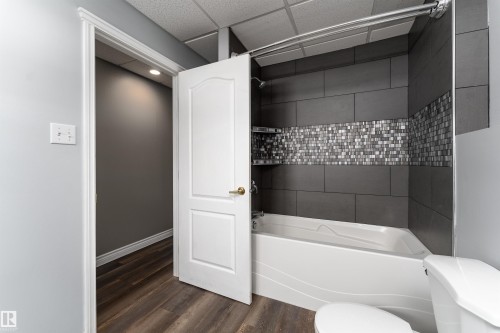 Bathroom featuring a white bathtub, dark gray subway tile, and a decorative mosaic tile accent - 4403 Yeoman Drive, Onoway, AB - Indoor Photo Showing Bathroom