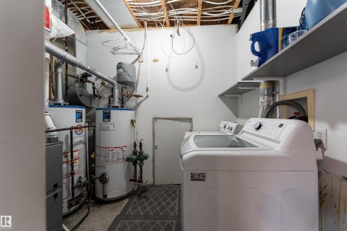 Utility area featuring two large water heaters, a washing machine, and wall-mounted shelving - 4403 Yeoman Drive, Onoway, AB - Indoor Photo Showing Laundry Room