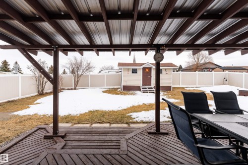 The property features a large backyard with a shed, a white privacy fence, and a wooden deck with a metal patio cover - 4403 Yeoman Drive, Onoway, AB - Outdoor With Deck Patio Veranda