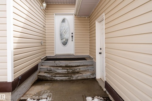 The property features neutral-toned siding, a white front door with an oval glass insert, and a separate white utility door - 4403 Yeoman Drive, Onoway, AB - Outdoor With Exterior